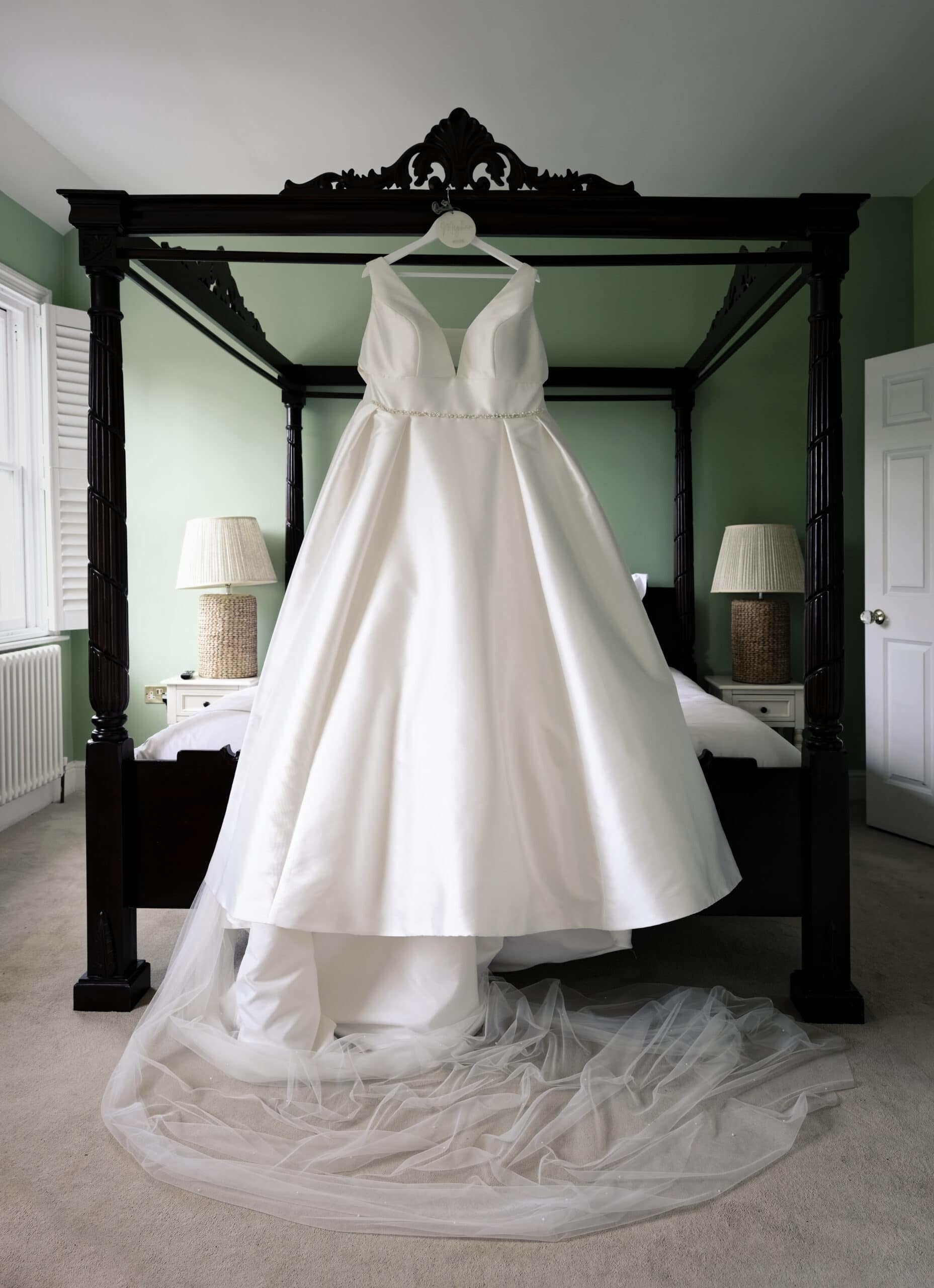Wedding dress hanging on a four-poster bed at Northbrook Park