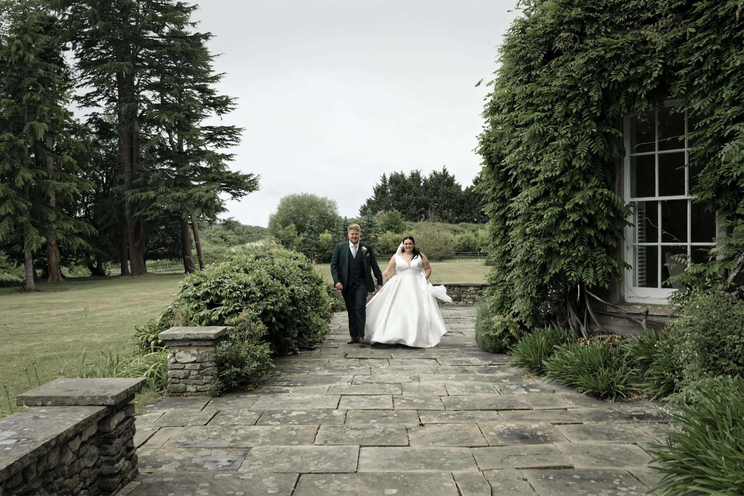 Bride and groom walking in golden evening light at Northbrook Park wedding photographer