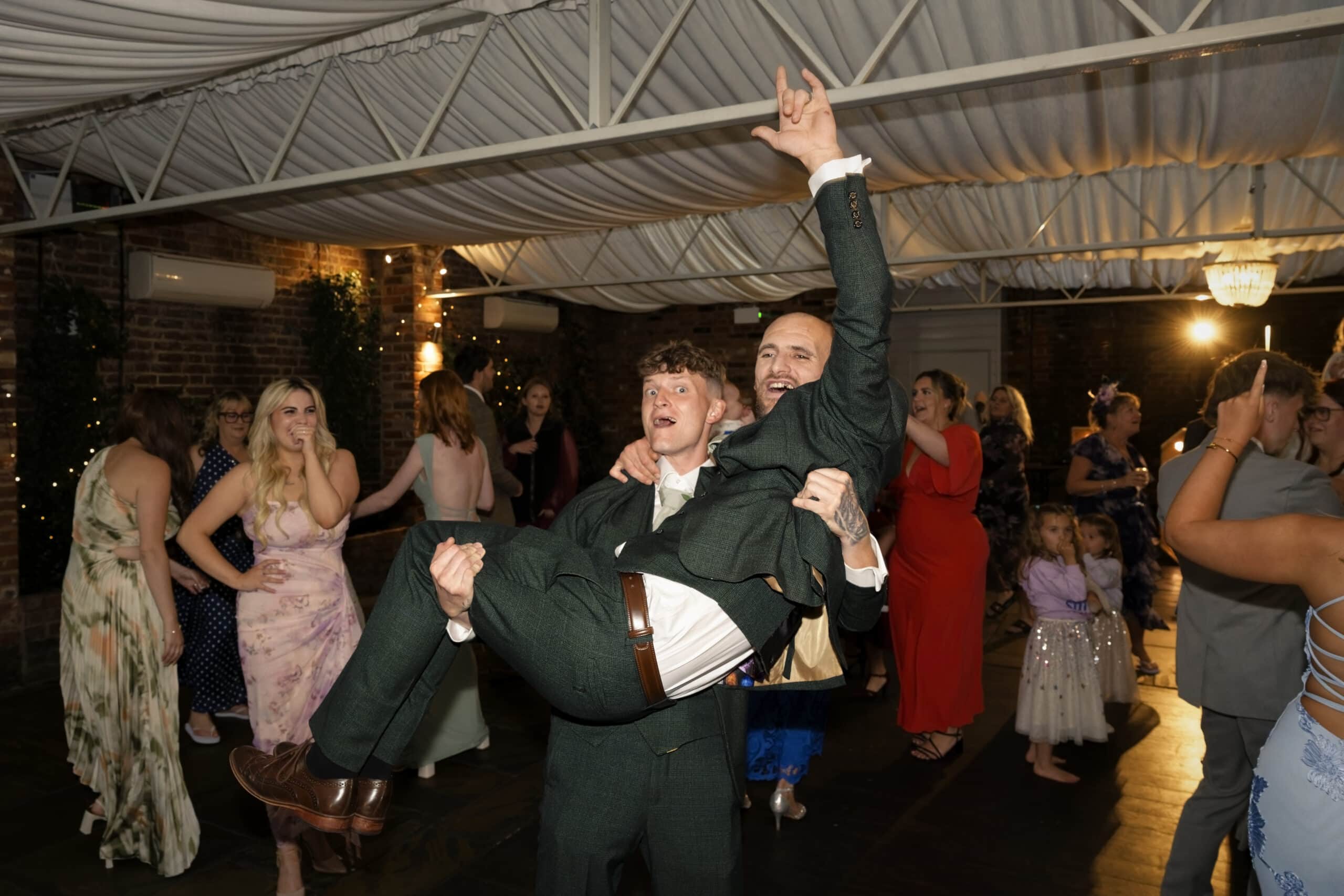 Groom lifted up by guests on the dance floor
