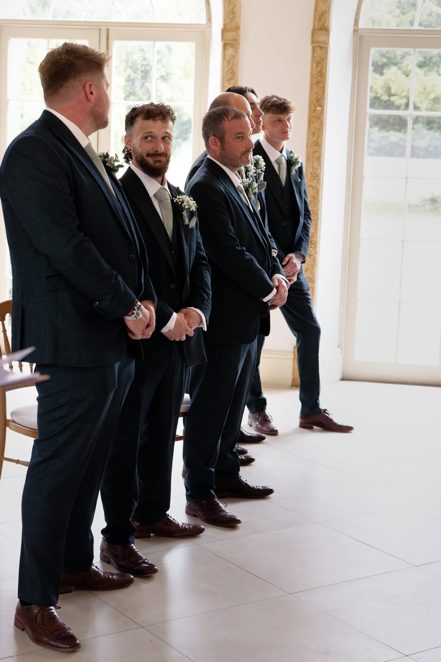Groomsmen standing at the front of the room awaiting the bride