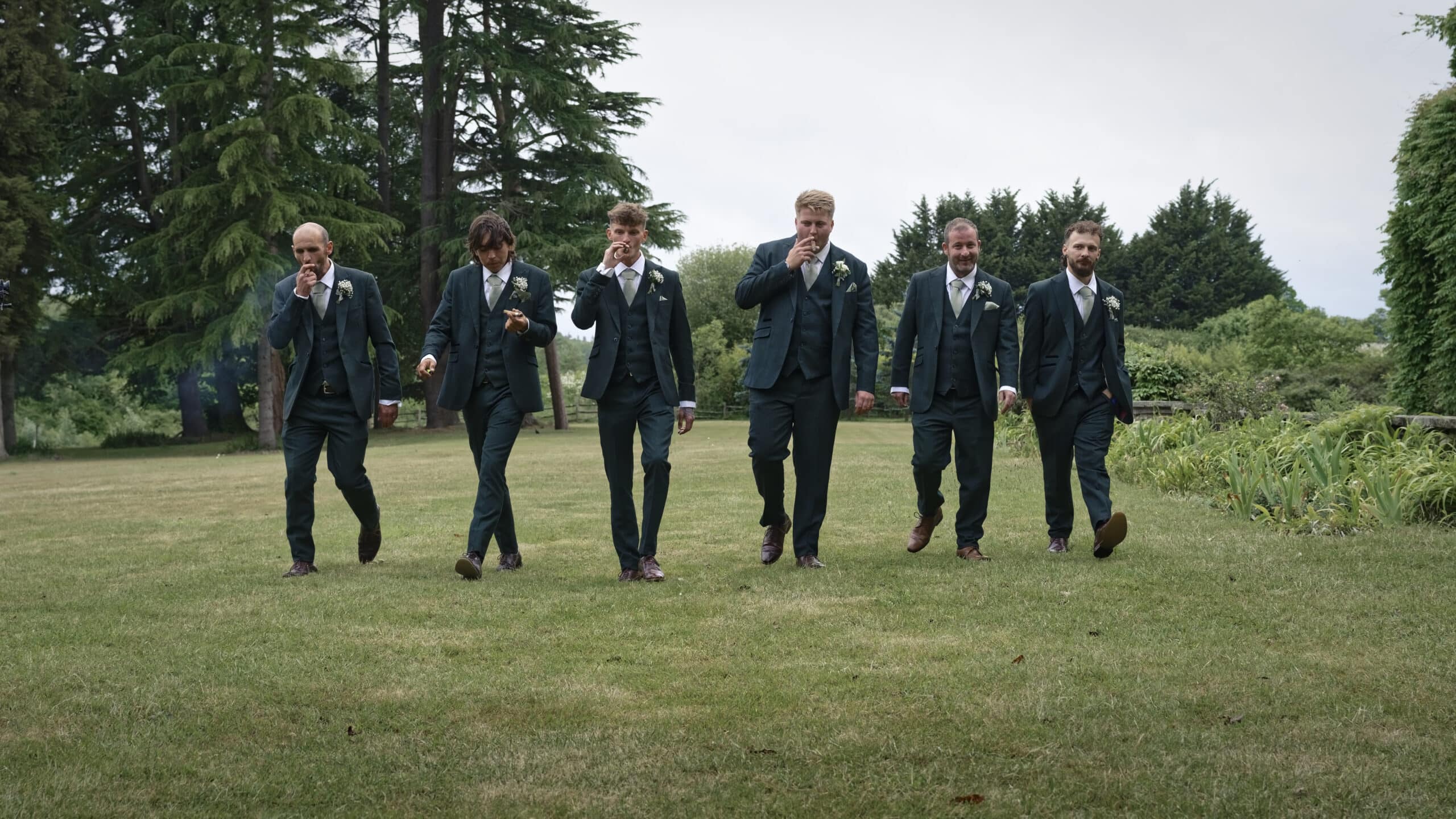 Groomsmen walking across the grounds in the evening