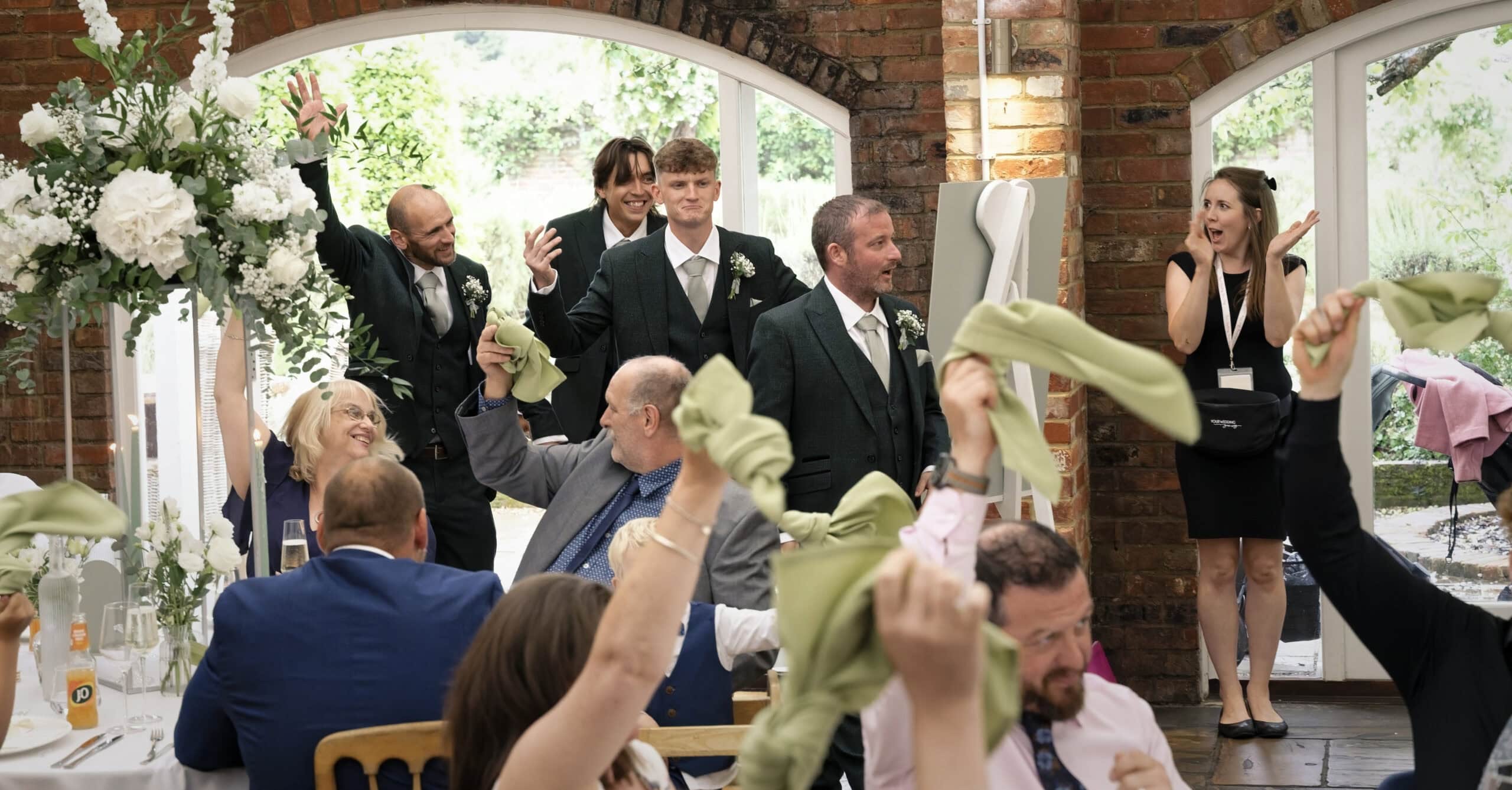 Guests waving green napkins as the bride and groom arrive for the wedding breakfast