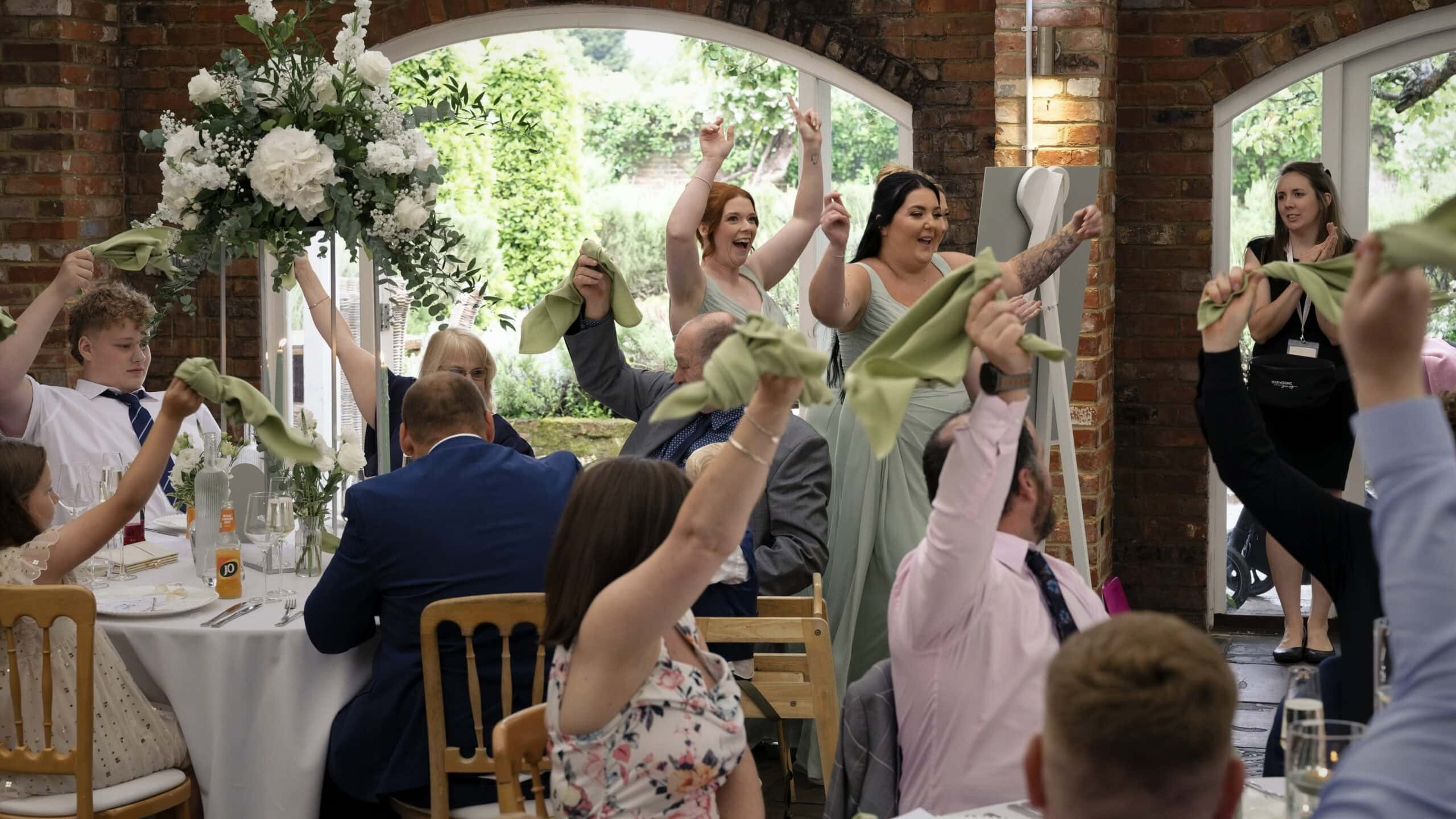 Guests waving green napkins as Meghan and Mark enter the wedding breakfast room