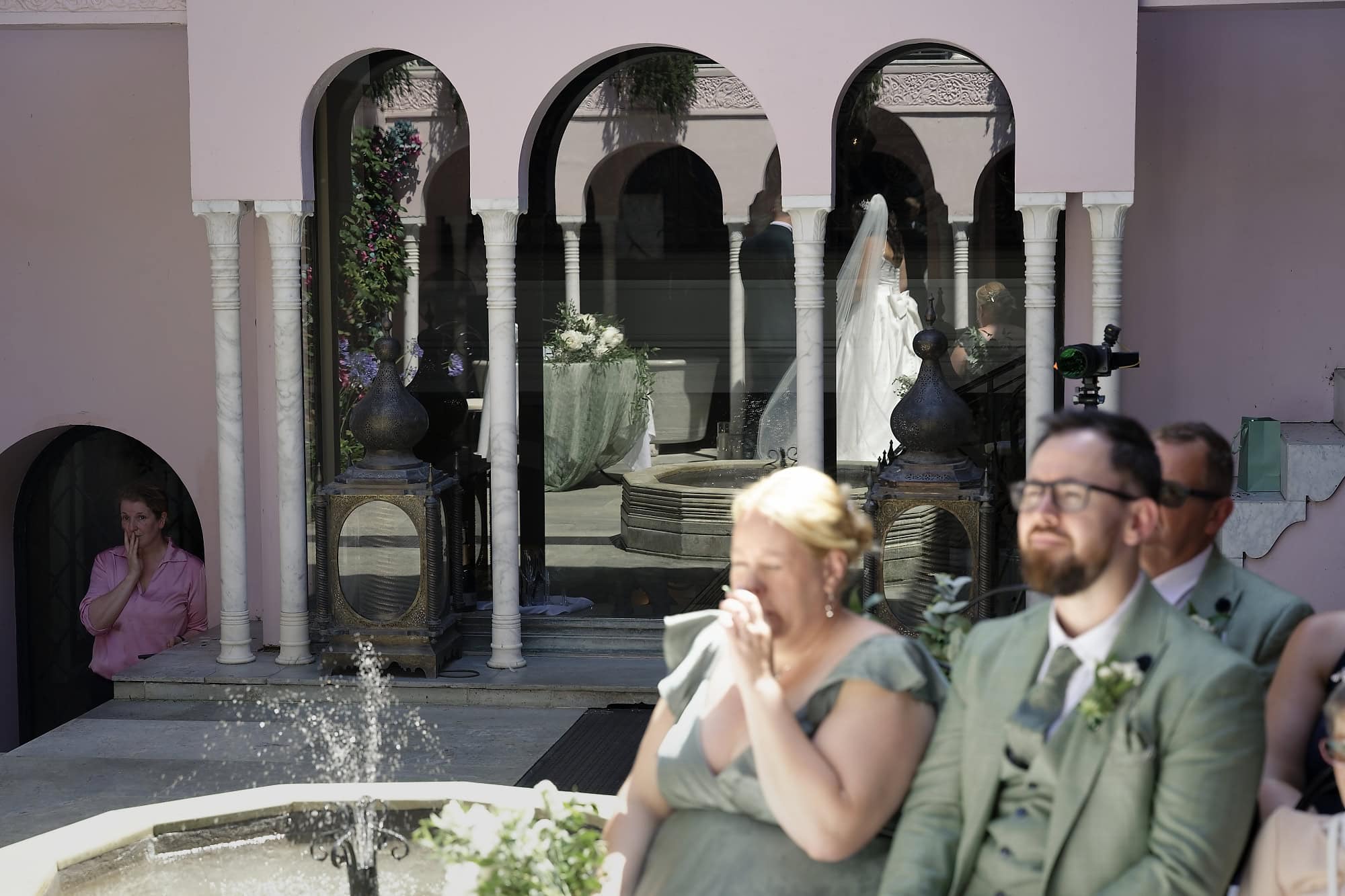 Guests emotional as the bride and groom's reflection appears in the courtyard windows during the ceremony