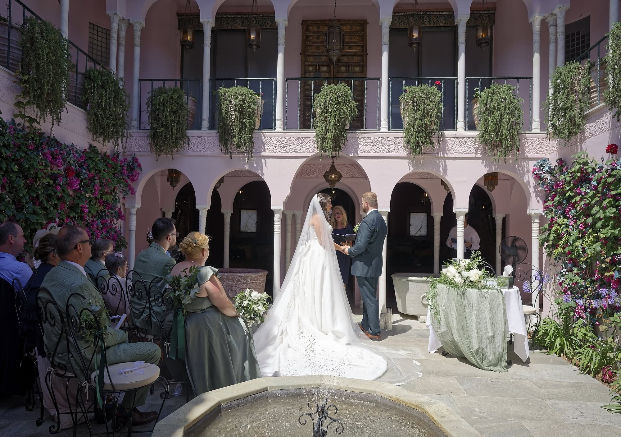 Wide view of Jade and Josh's wedding ceremony in the Moroccan Courtyard, family looking on