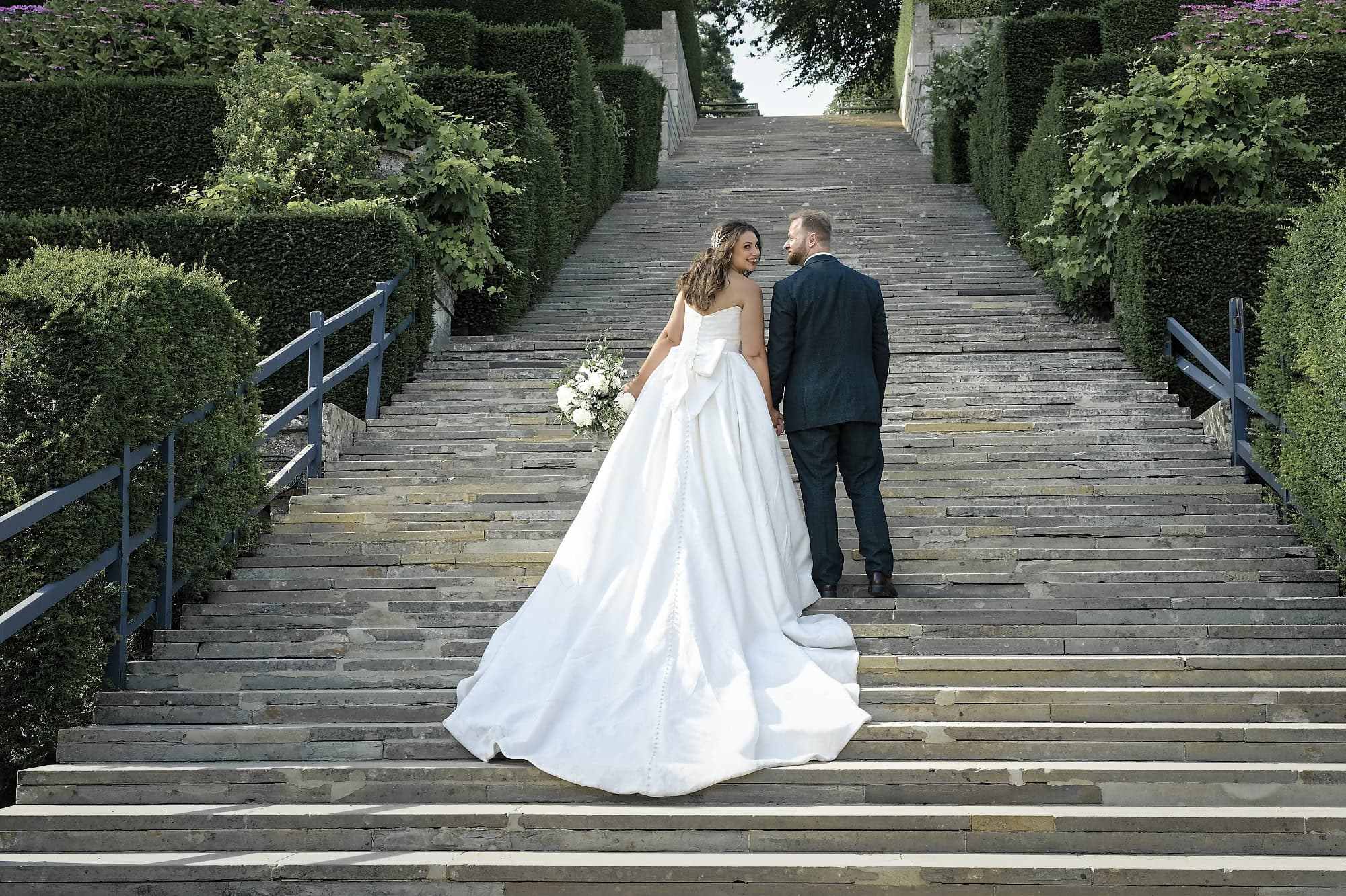 Newlyweds laughing together on the grand steps at Port Lympne
