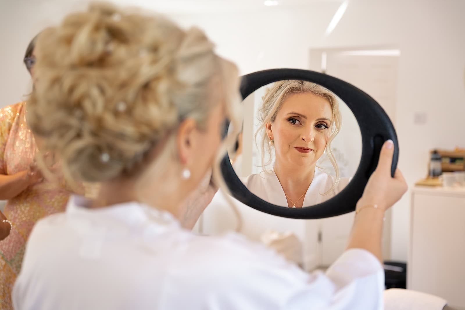 Bride's reflection in a hand mirror during hair and makeup at The Ravenswood