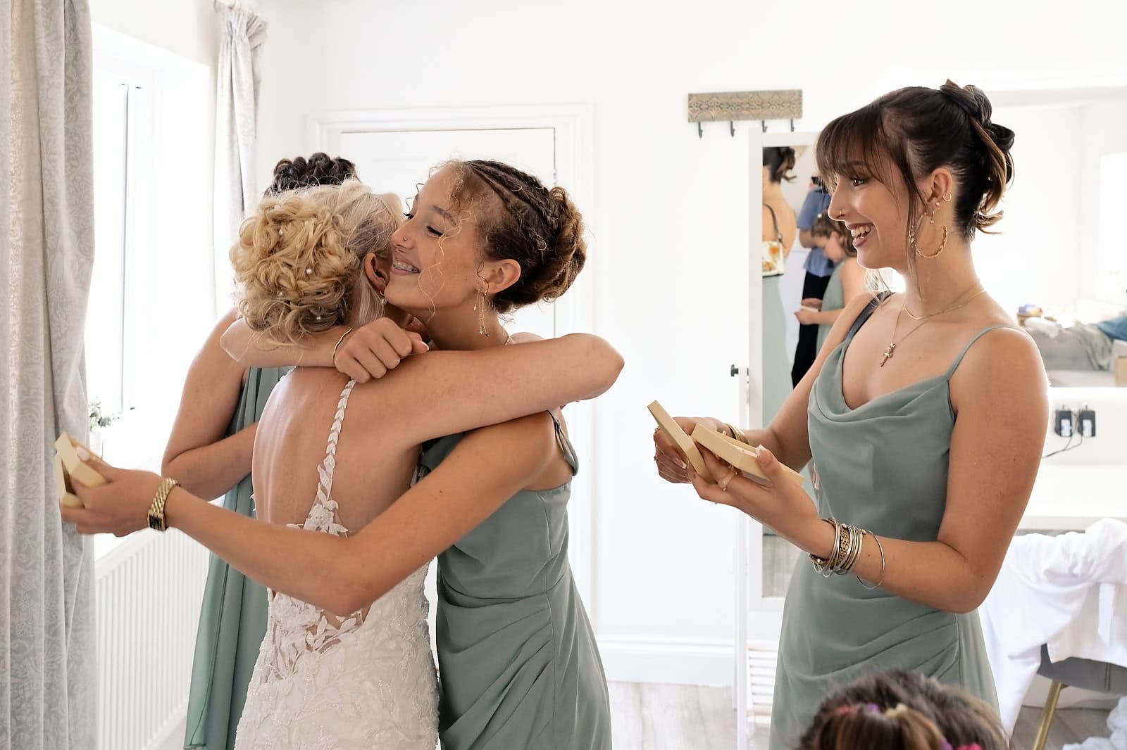 Bride embracing a bridesmaid in sage green during getting ready at The Ravenswood