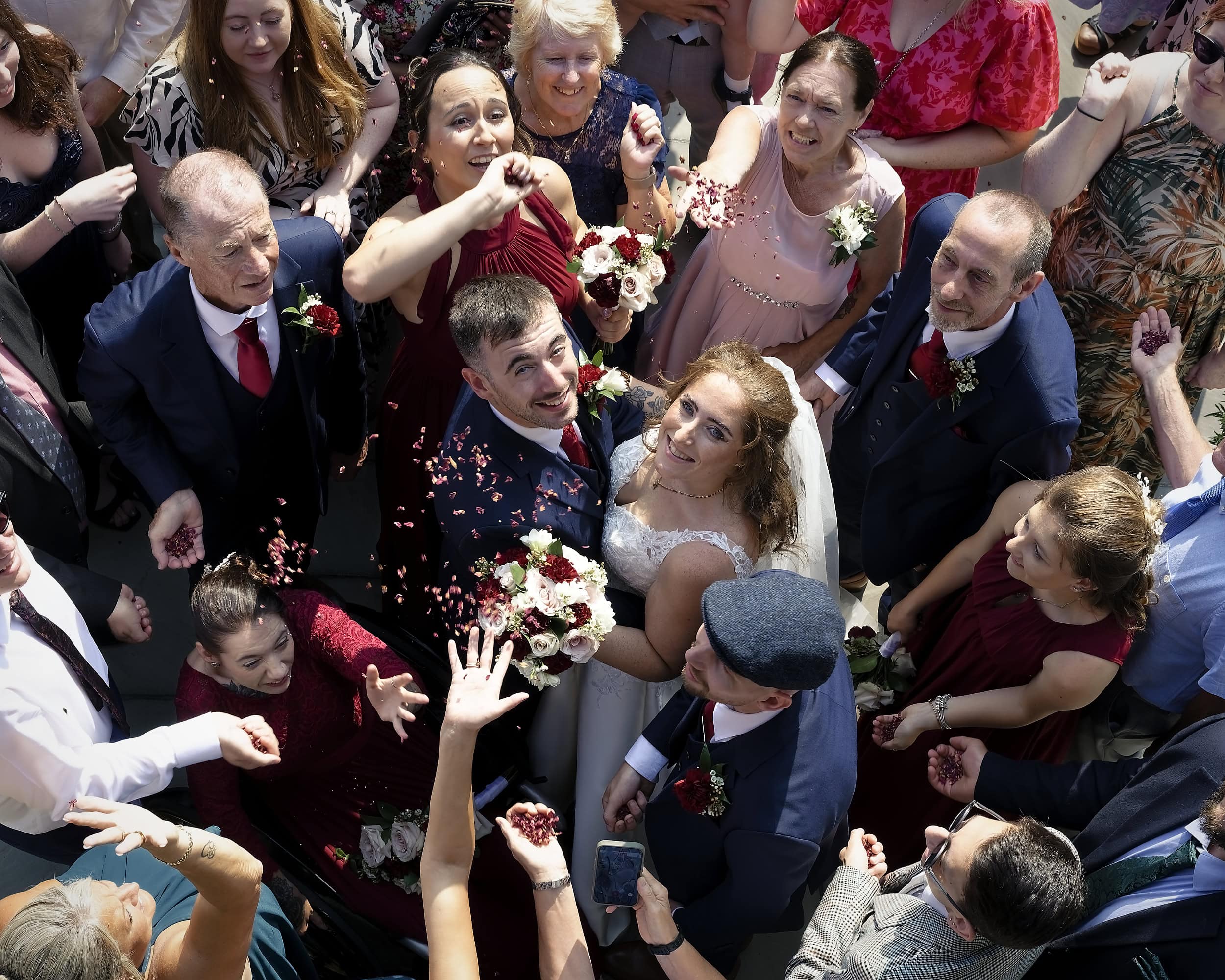 Bride and groom surrounded by smiling guests throwing confetti, photographed from above at the Cottesmore Hotel