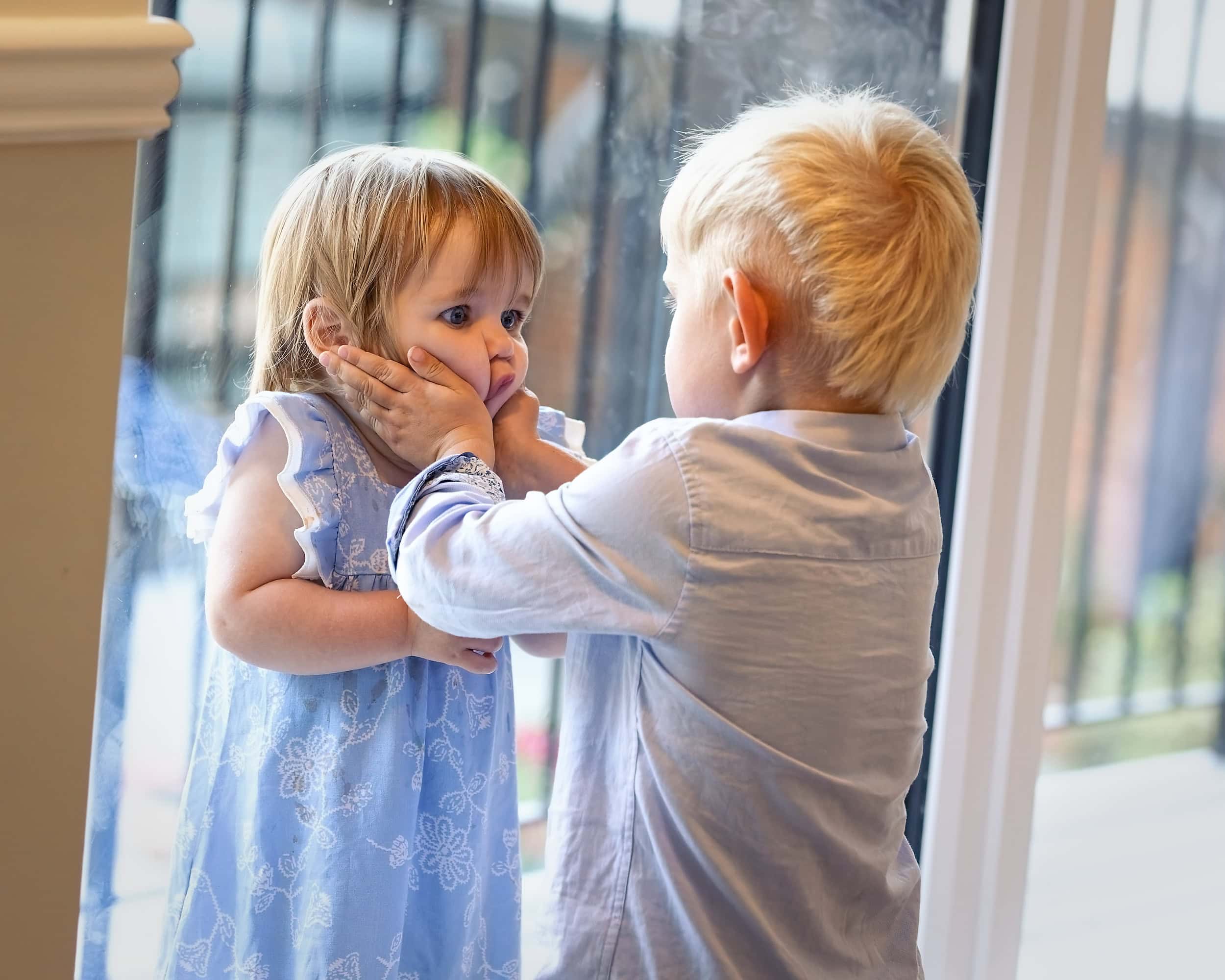 Two young children sharing a surprised moment by a window at a Cottesmore Hotel wedding