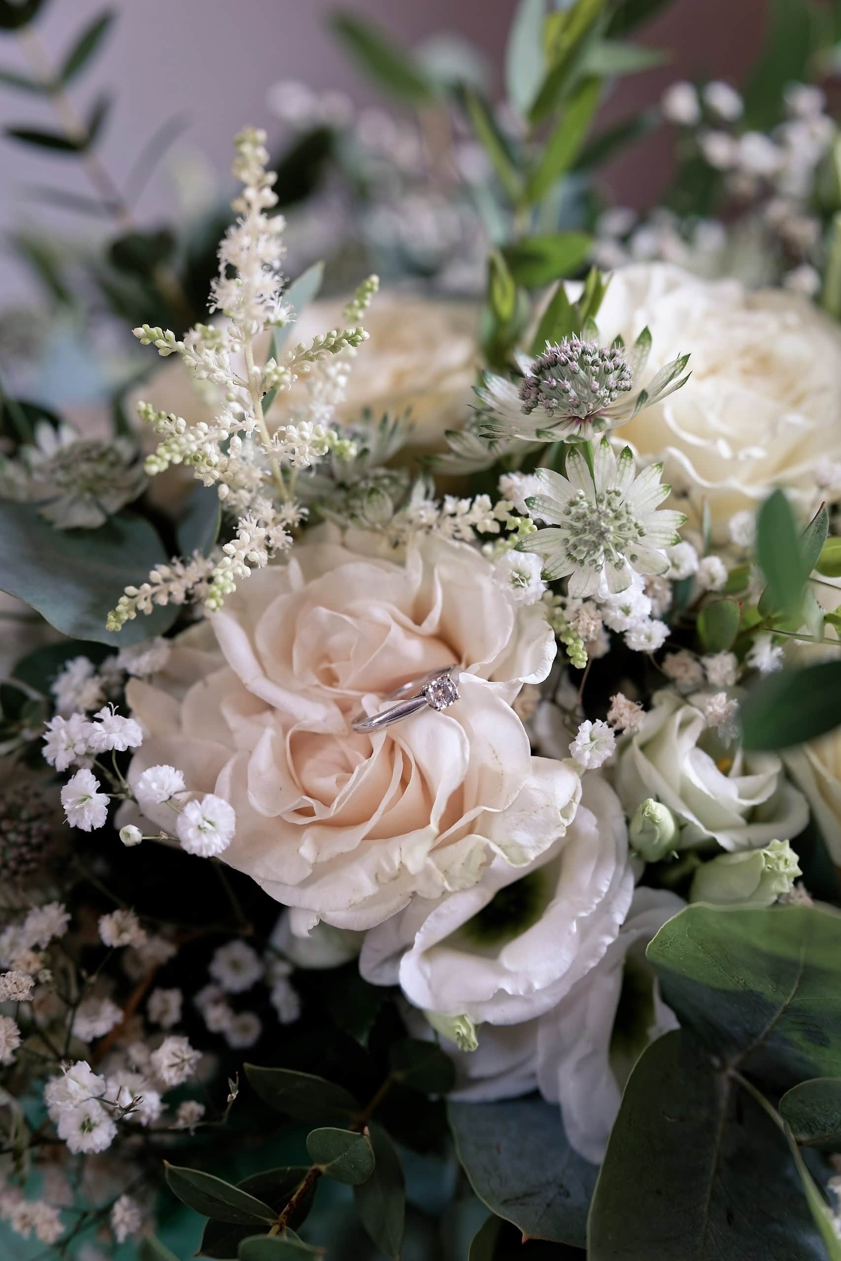 Engagement ring nestled in a bouquet of blush roses and greenery at a Grittenham Barn wedding