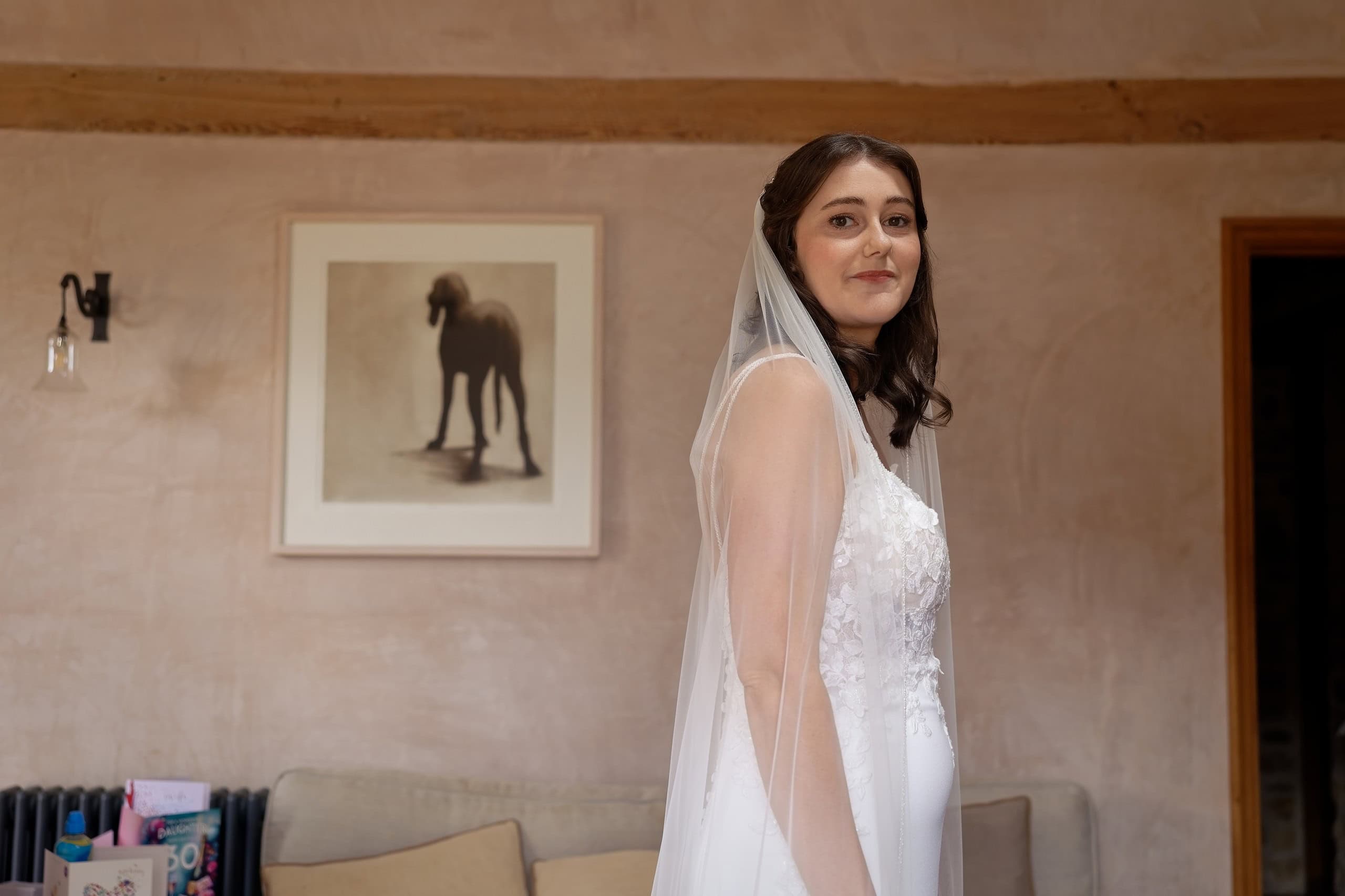 Bride in her veil glancing back over her shoulder, ready for her West Sussex church wedding