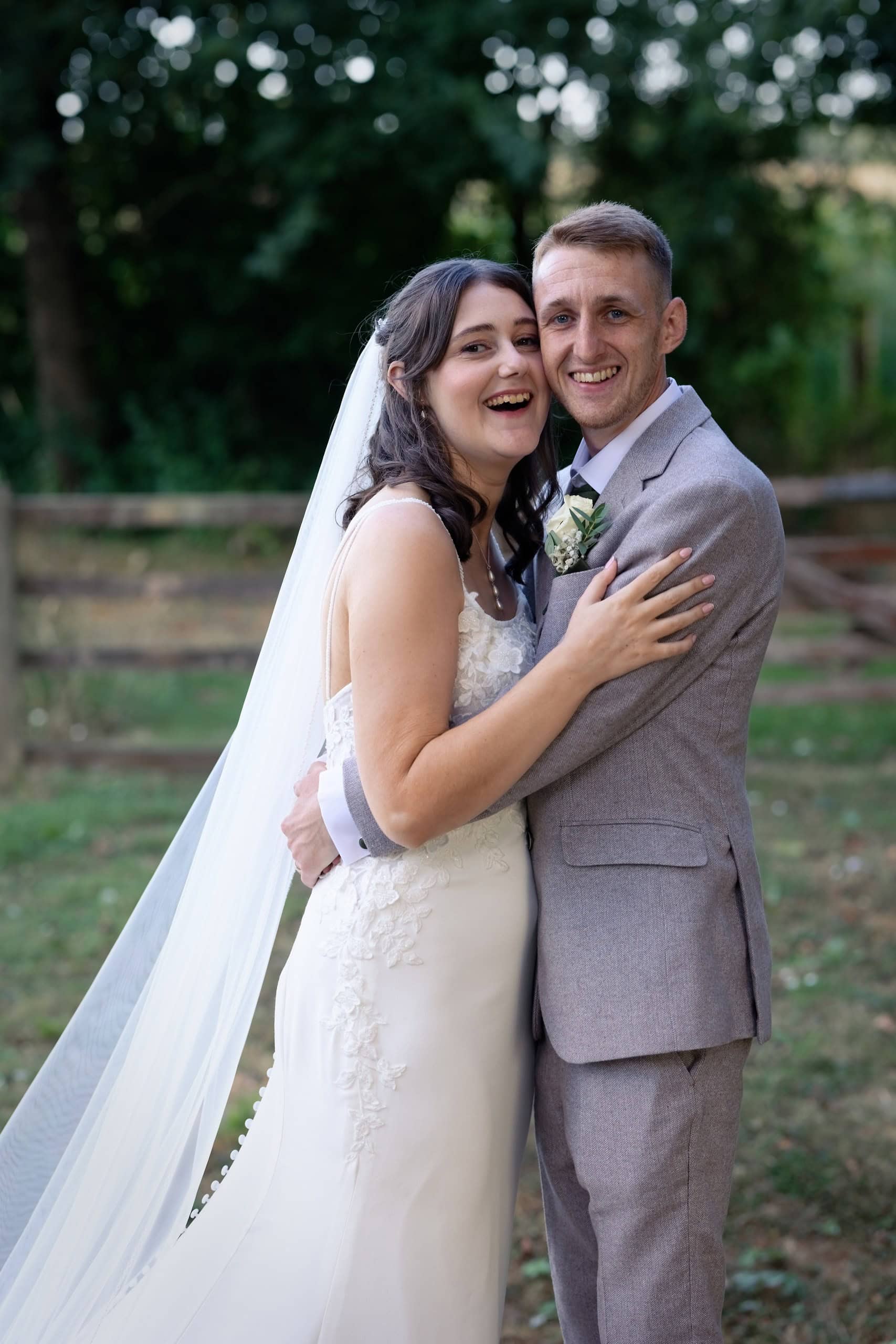 Joyful cheek to cheek portrait of the bride and groom at Grittenham Barn