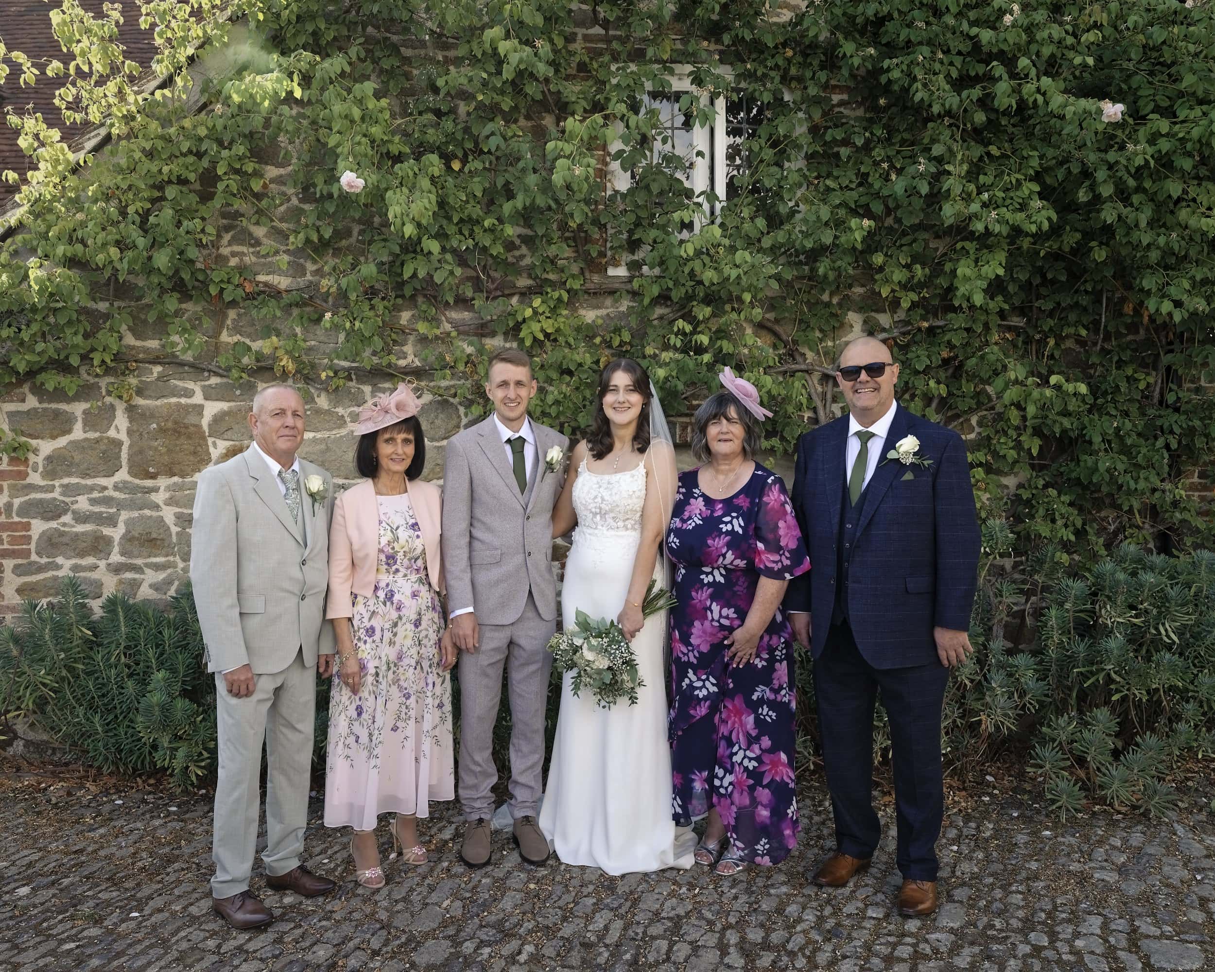 Relaxed family group photo against the ivy covered stone wall at Grittenham Barn