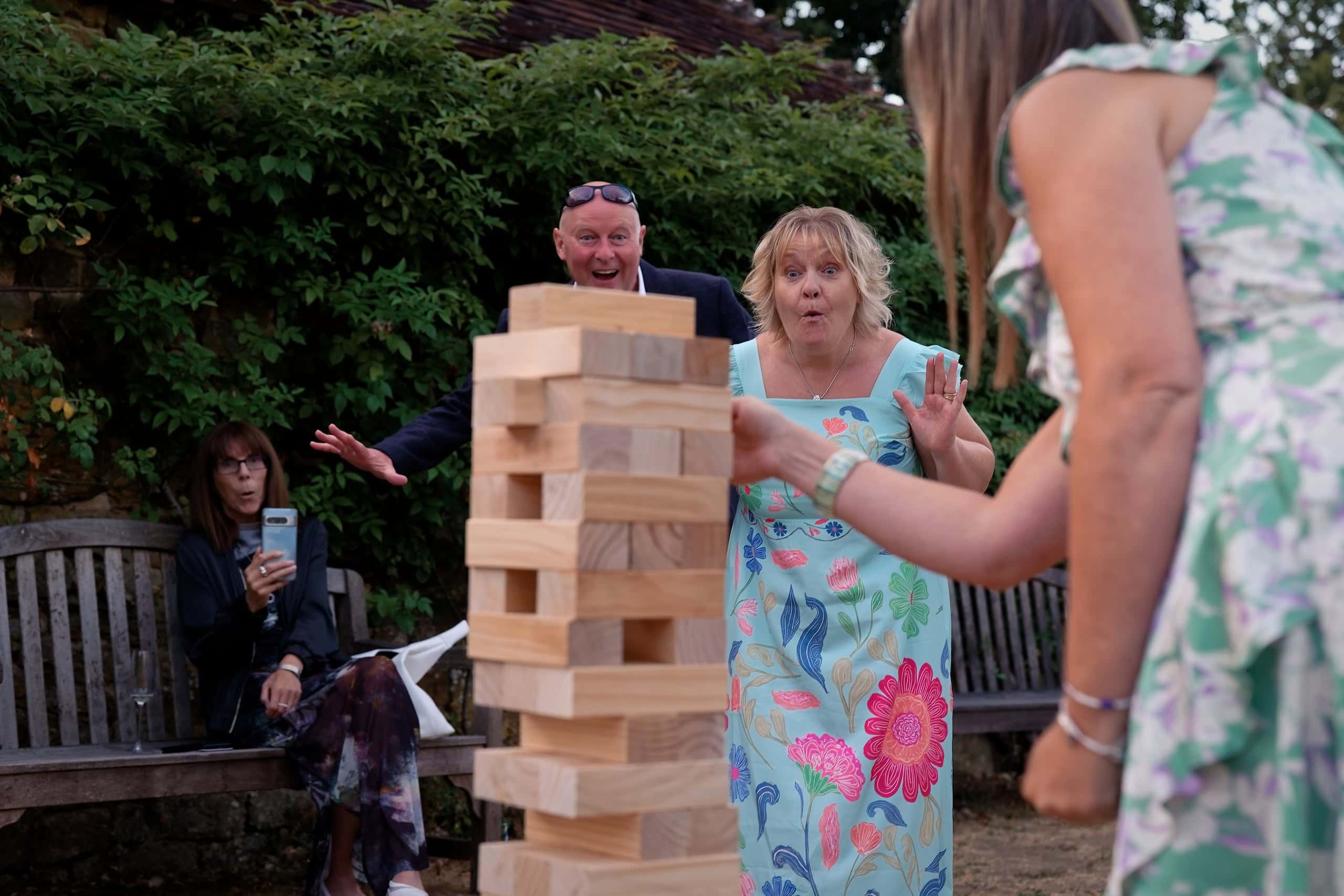 Guests gasping as a giant Jenga tower wobbles during the wedding reception