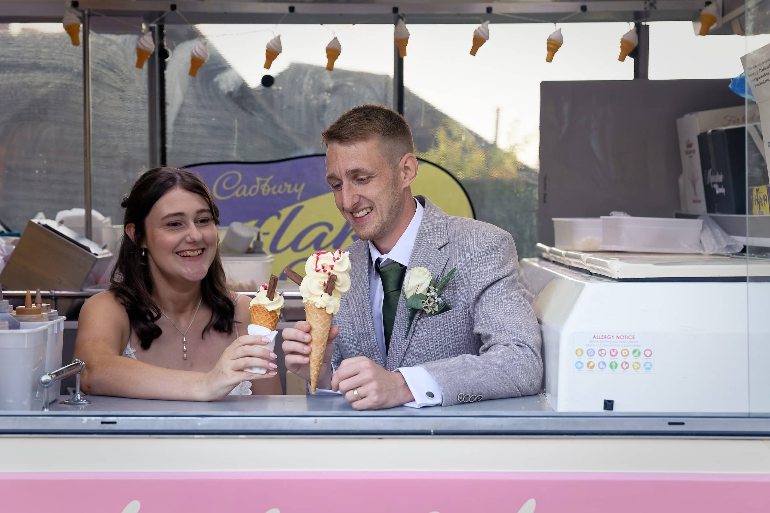 Newlyweds laughing over their ice cream cones in the van at Grittenham Barn