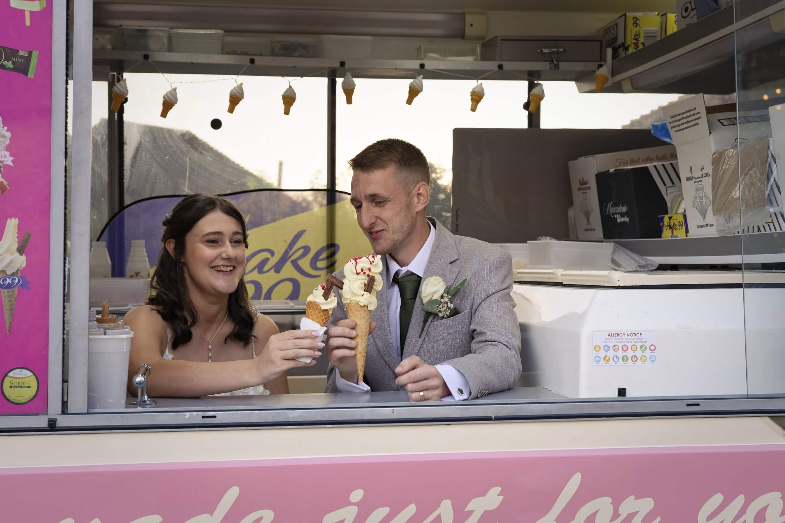 Bride and groom with ice cream cones inside the T&M Ices van at their wedding