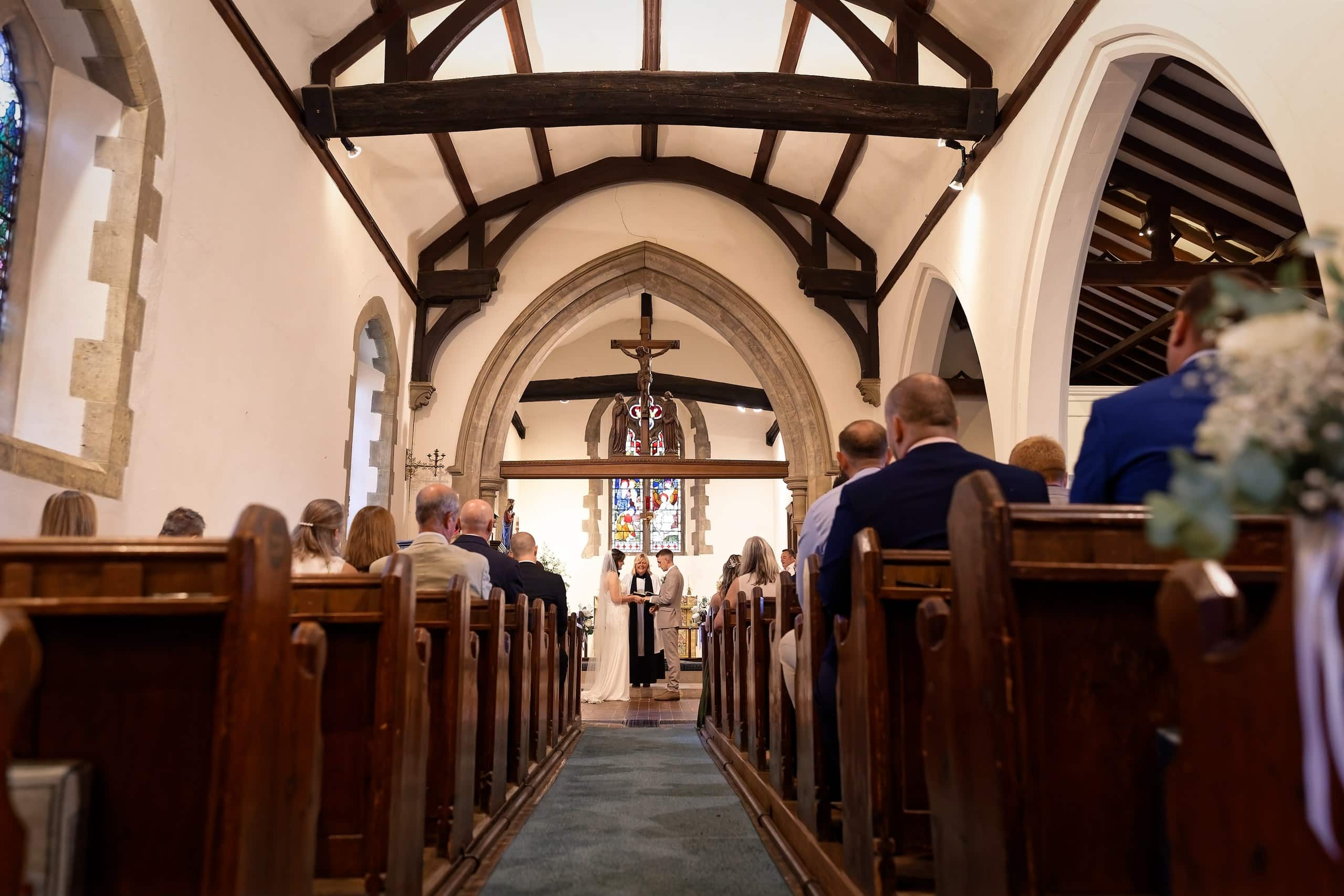 View down the aisle of St Margaret of Antioch Church during the wedding service