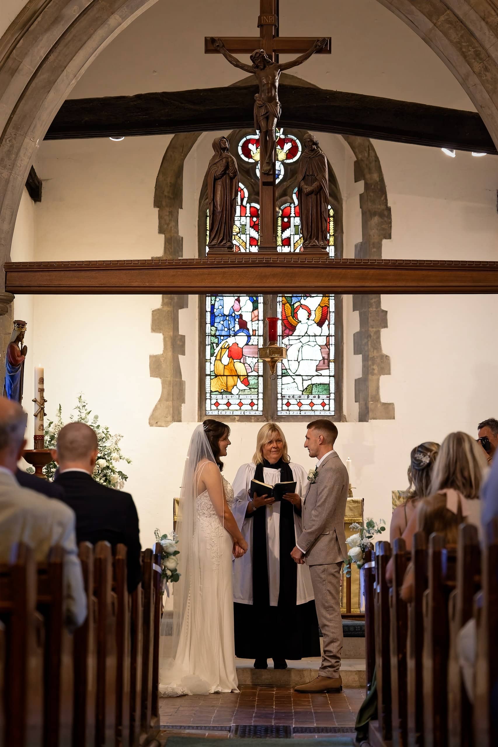 Couple at the altar beneath the stained glass window of St Margaret of Antioch Church