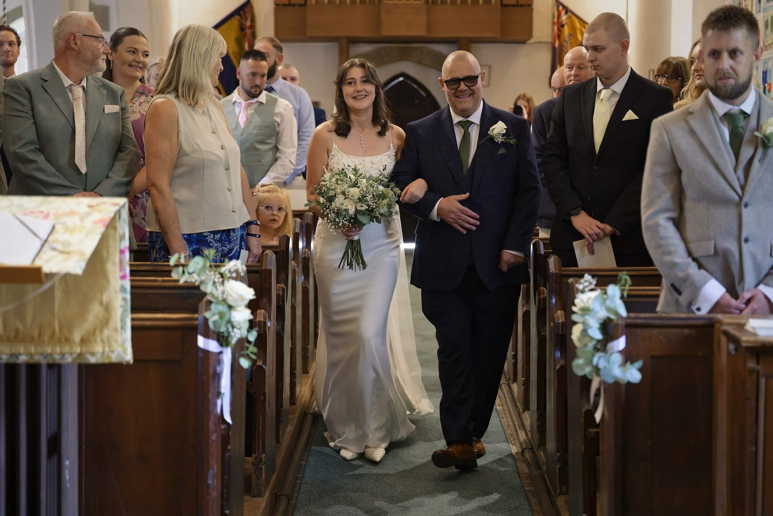 Bride walking down the aisle with her dad at St Margaret of Antioch Church, Fernhurst