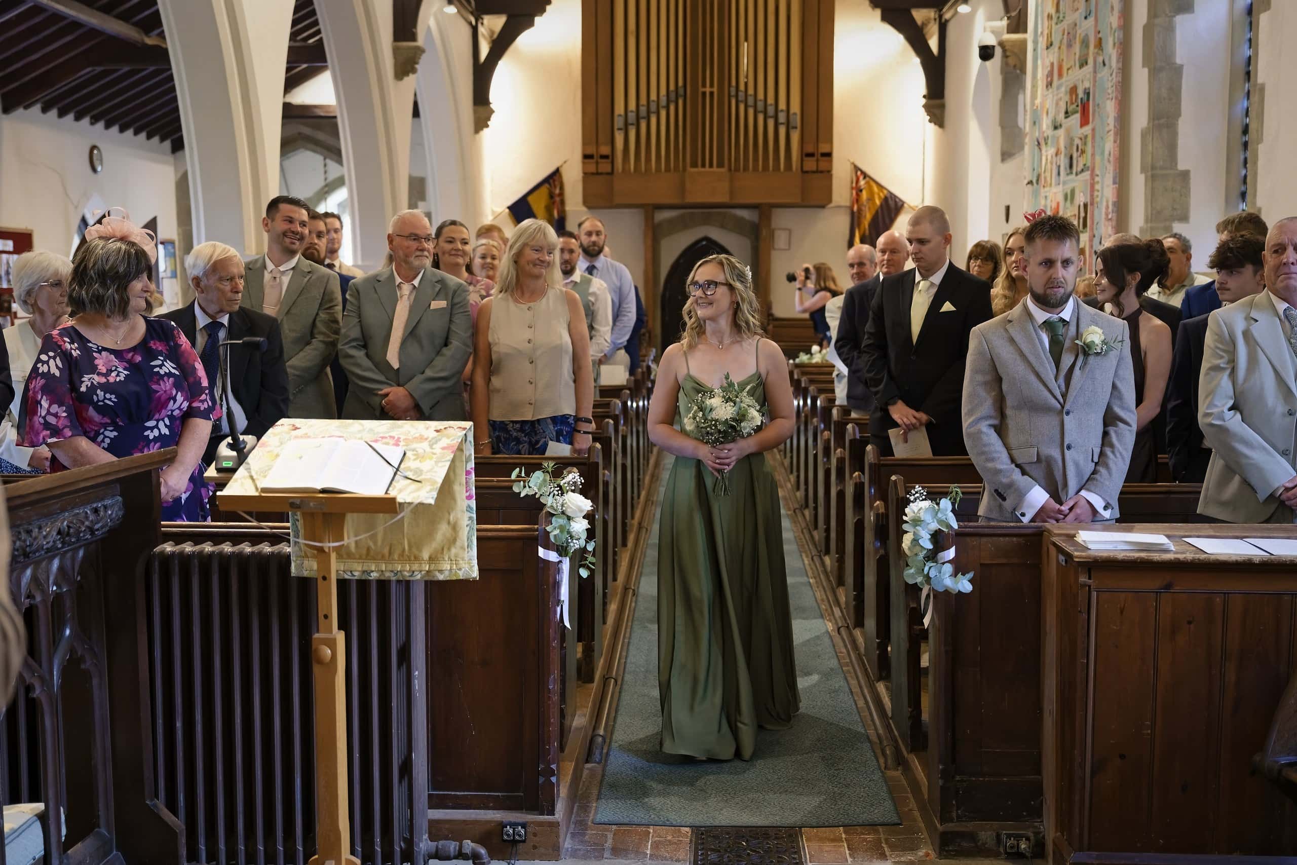 Maid of honour walking down the aisle at St Margaret of Antioch Church in Fernhurst