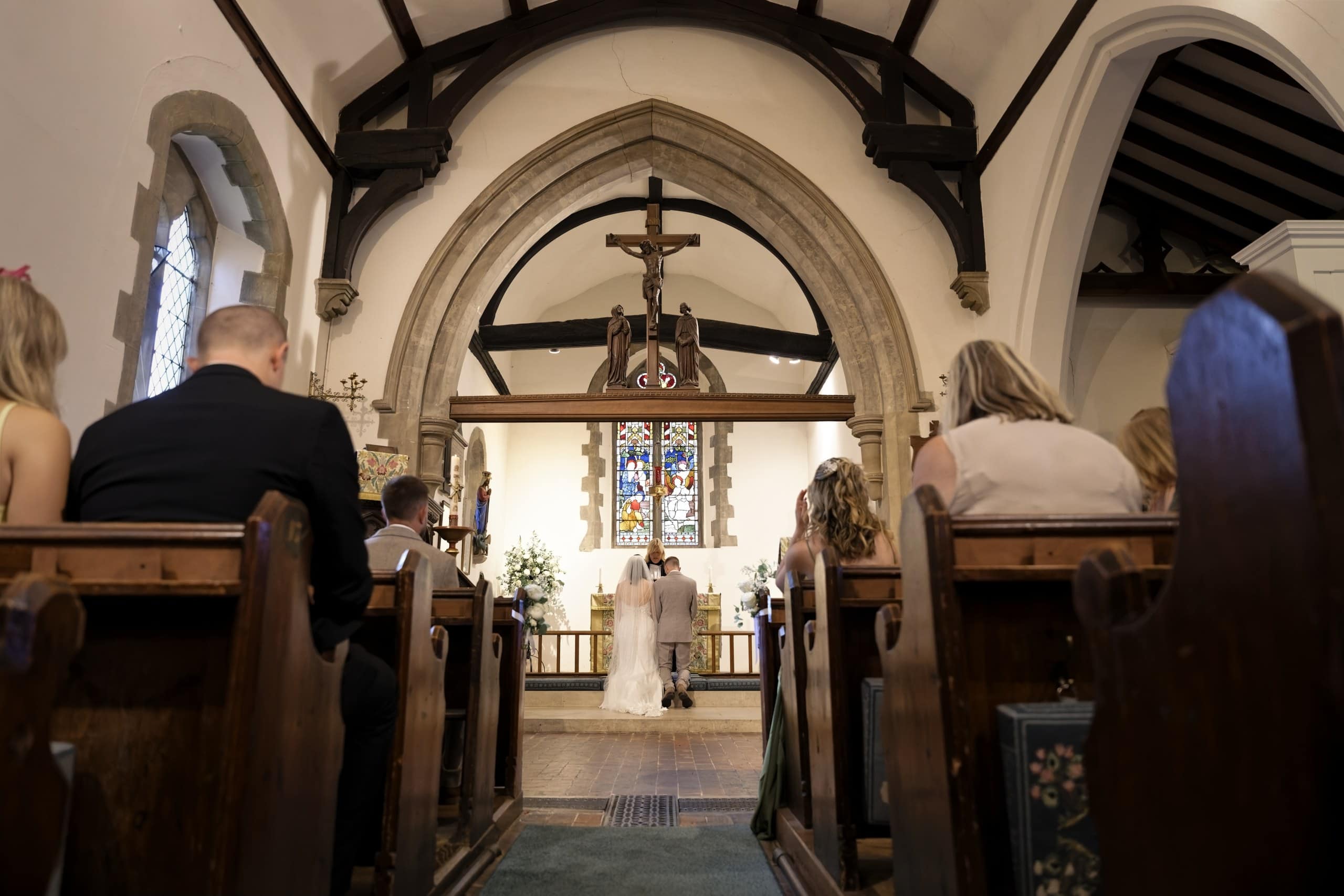 Couple at the altar seen from the back of the church between the wooden pews