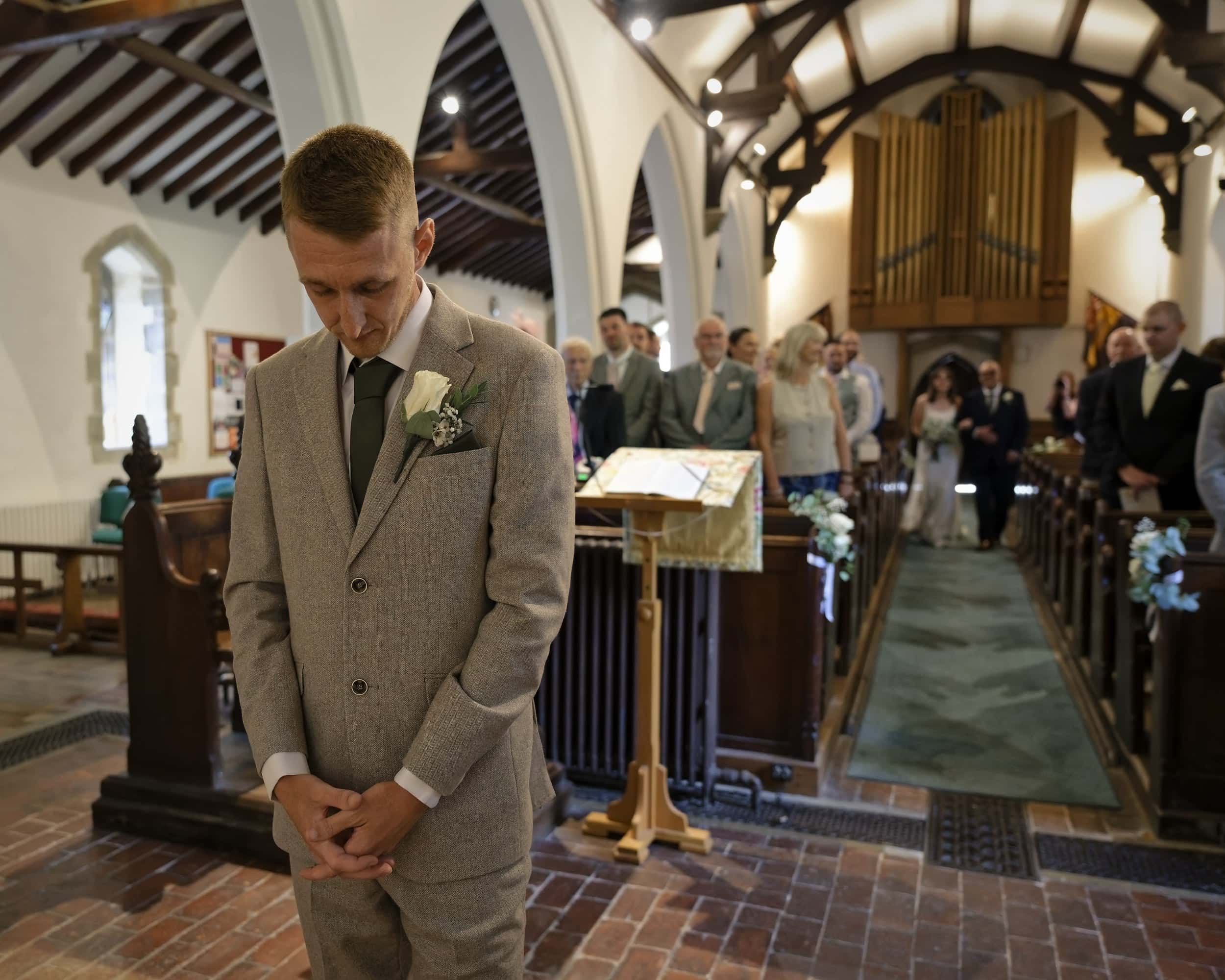 Groom waiting with his head bowed at the front of St Margaret of Antioch Church